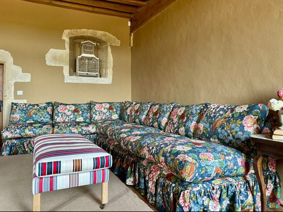 Floral-patterned sofa in a room with a rustic ceiling and wall.