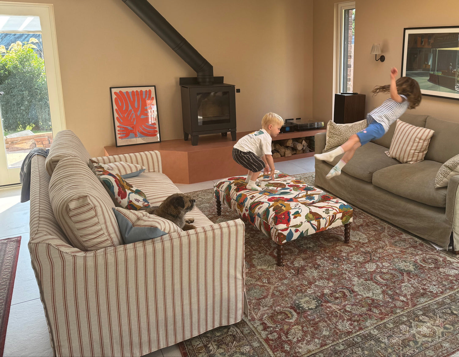 Living room with two children playing on a Sonder sofa and Wish ottoman surrounded by furniture and decor.